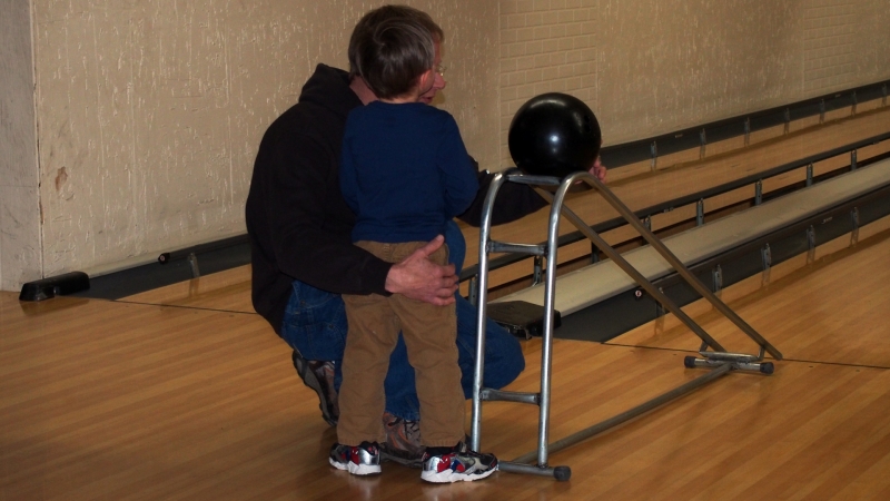 Dad consoling Jakob after his finger was pinched by the bowling ball